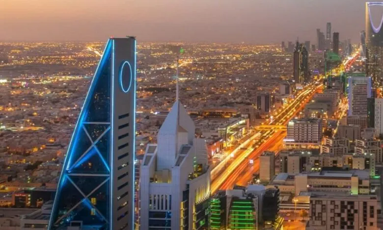 Nighttime aerial view of Riyadh, Saudi Arabia, showcasing illuminated skyscrapers and city lights.