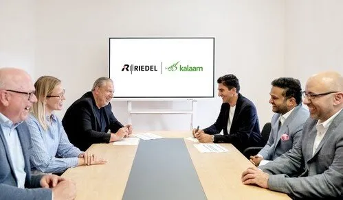 Riedel and kalaam representatives smiling at a signing ceremony.