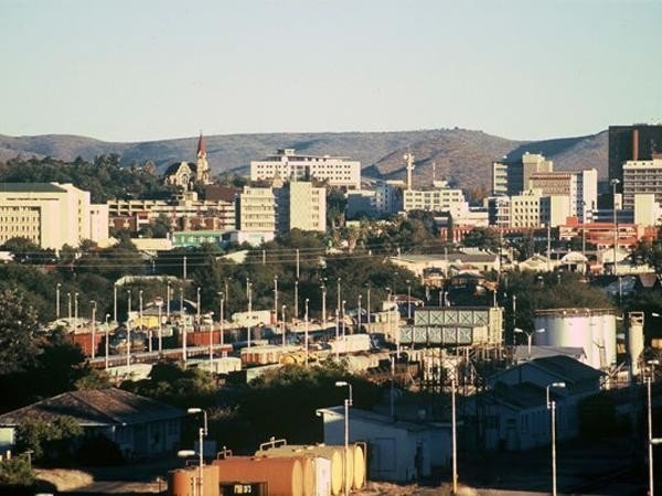 Cityscape view of Maseru, Lesotho, showing buildings, mountains, and a railway yard.