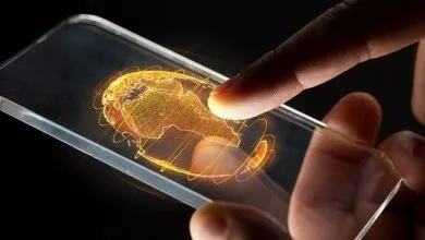 Hand interacts with a transparent phone displaying a glowing orange world map.