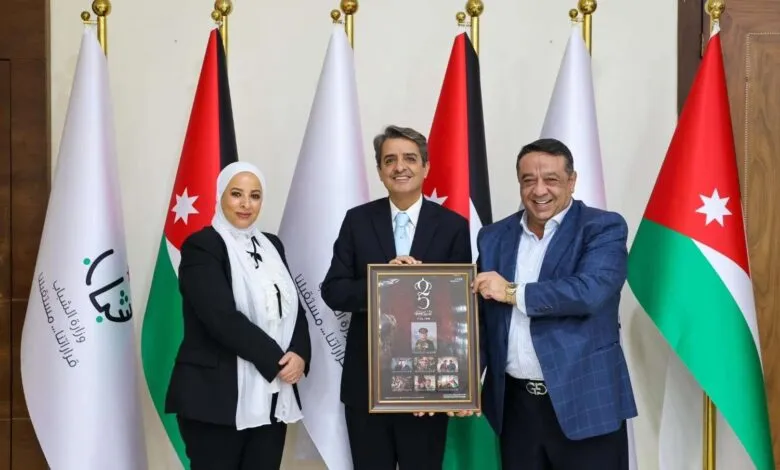 Three people stand in front of Jordanian flags, holding a framed document.