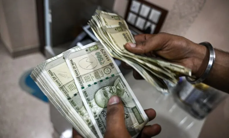 Hands holding stacks of Indian 500 rupee banknotes.