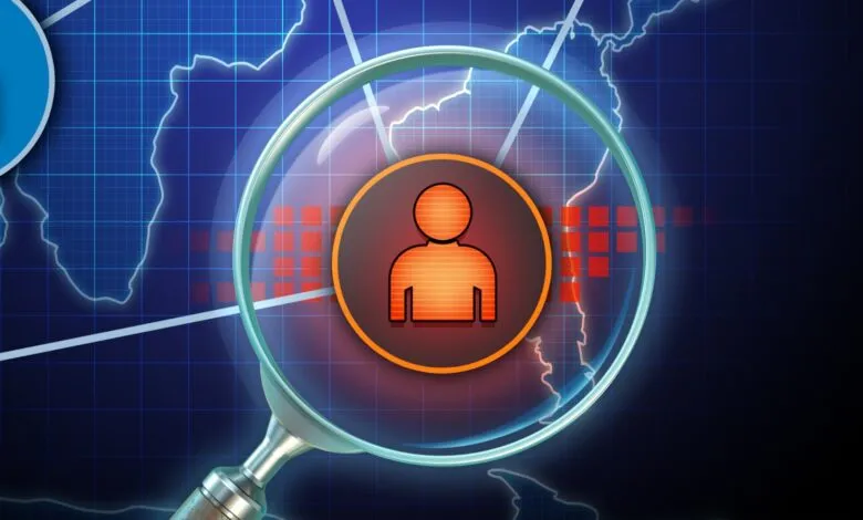 Magnifying glass focuses on a person icon over a world map, highlighting insider threat detection.