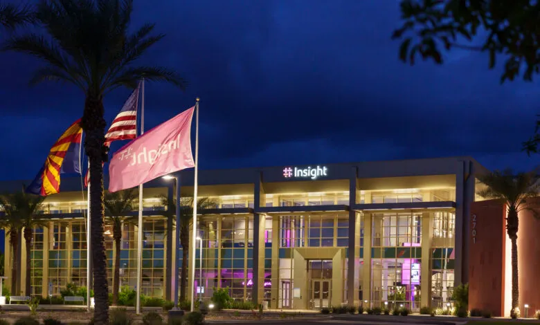 Insight company building exterior at dusk with flags and palm trees.