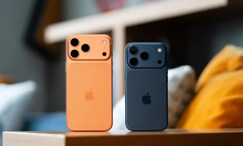 Copper and dark blue iPhone 17 Pro Max models shown from the back, sitting on a wooden surface.