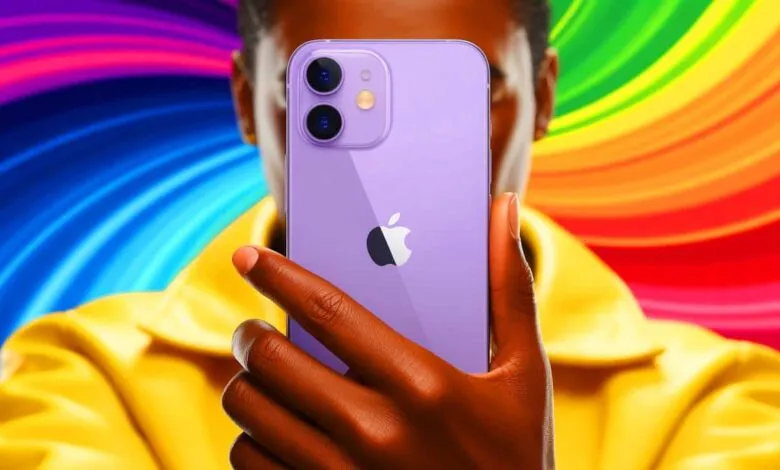 Person holding a purple iPhone with the Apple logo visible against a vibrant rainbow background.