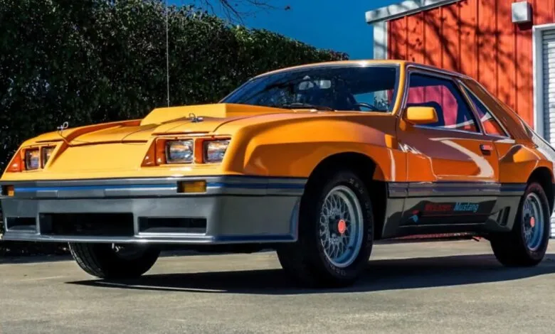 Bright orange McLaren Mustang with a prominent hood scoop parked outdoors.
