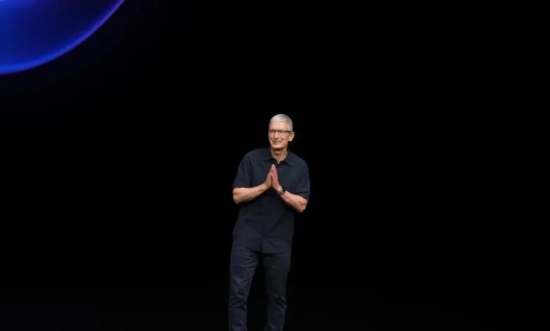 Tim Cook, Apple CEO, on stage at a product launch event, hands clasped.