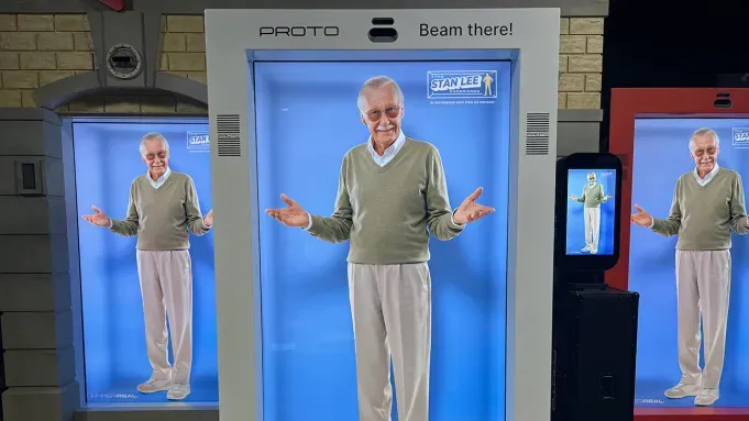 Holographic projection of Stan Lee in a museum exhibit, welcoming visitors.