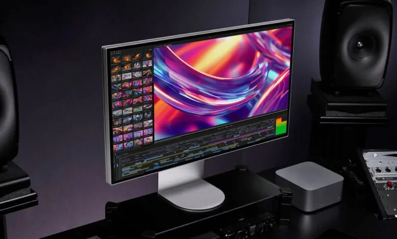A sleek Apple Studio Display shows video editing software with colorful abstract graphics.