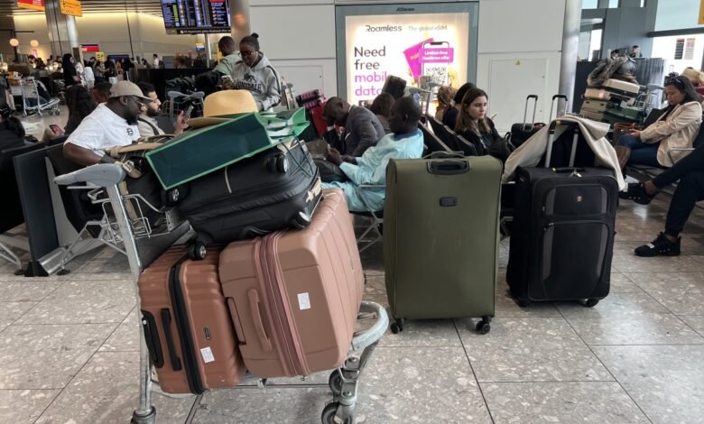 Passengers with luggage wait in a crowded Heathrow Airport terminal.