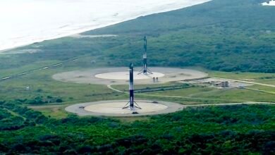 Two SpaceX Starship rockets stand on launchpads near a coastline.