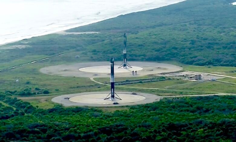 Two SpaceX Starship rockets stand on launchpads near a coastline.