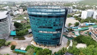 Aerial view of a modern, curved glass office building with teal-tinted windows.