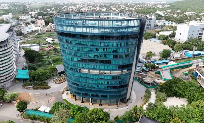 Aerial view of a modern, curved glass office building with teal-tinted windows.