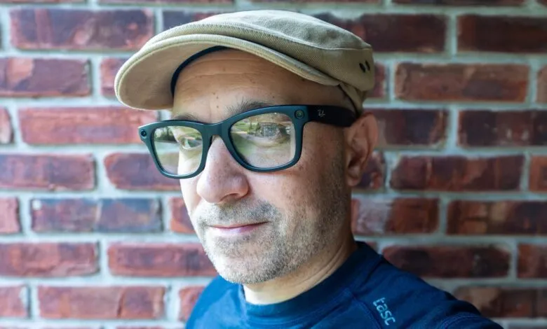 Close-up of a man wearing Ray-Ban smart glasses and a newsboy cap against a brick wall.