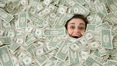 Woman's face emerges from a pile of one-dollar bills, expressing surprise or excitement.