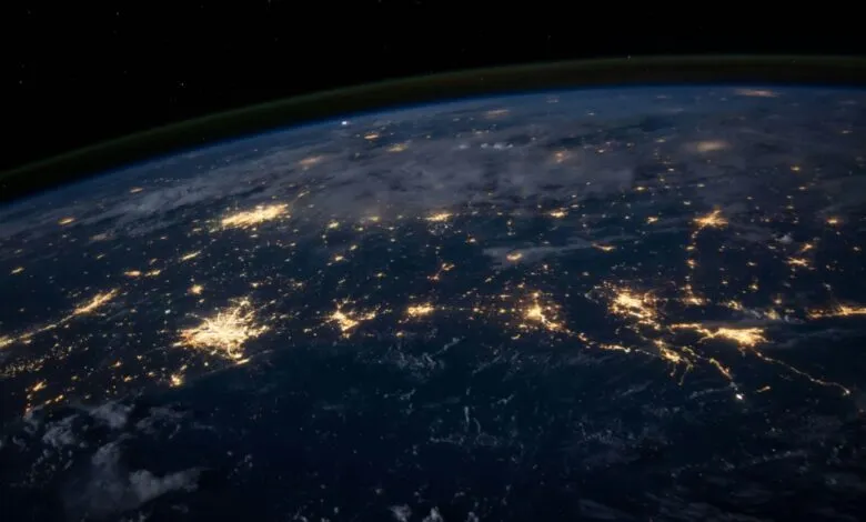 Earth at night, viewed from space, showing city lights illuminating the planet's surface.