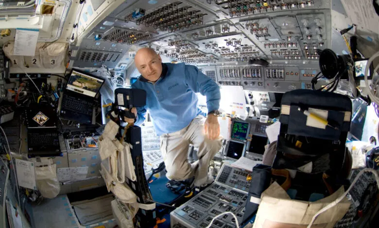 Astronaut Scott Kelly in the International Space Station cockpit, holding a camera.