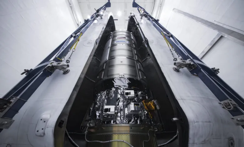A silver spacecraft inside a large, open metallic structure, possibly in a hangar.