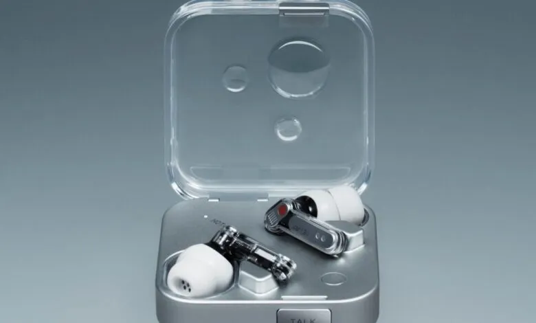 Wireless earbuds in a sleek, silver charging case. The case is transparent and shows the earbuds inside.