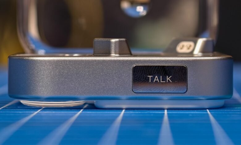 Close-up of a silver device with a 'TALK' button, resting on a blue surface.