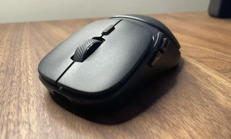 Close-up of a black wireless computer mouse with a textured scroll wheel on a wooden desk.