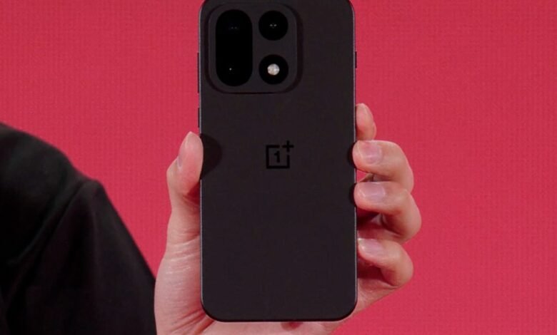 Close-up of a person holding a black OnePlus 15 smartphone against a red background.
