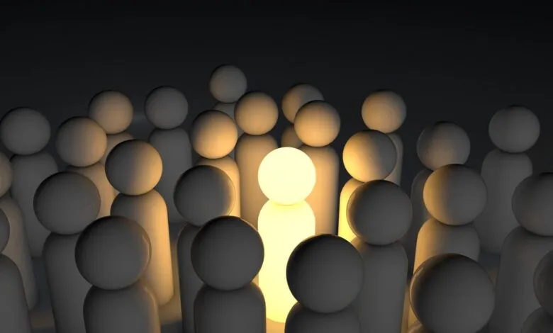 One glowing figure stands out among a crowd of dark figures, symbolizing leadership or individuality.