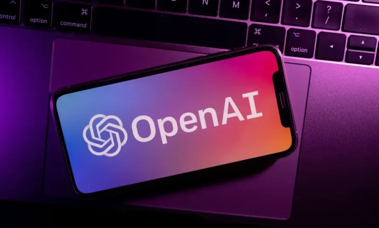OpenAI logo displayed on a smartphone resting on a laptop keyboard.