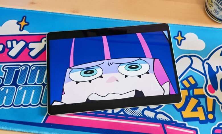 Tablet displaying an anime character with wide eyes and pink hair on a colorful desk mat.