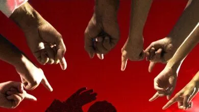 Multiple hands pointing downwards at a shadowed figure on a red background, symbolizing blame or judgment.