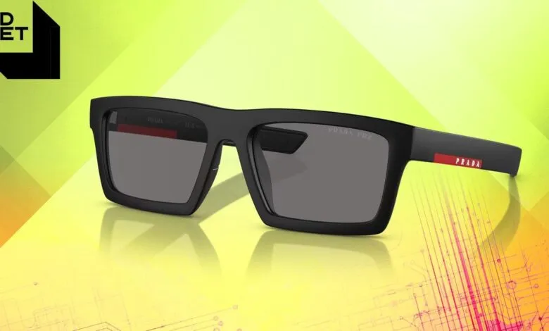 Prada Linea Rossa sunglasses: sleek black frames with gray lenses, red Prada logo on the temple.