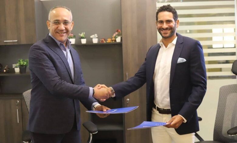 Two businessmen in suits shaking hands over documents in an office.