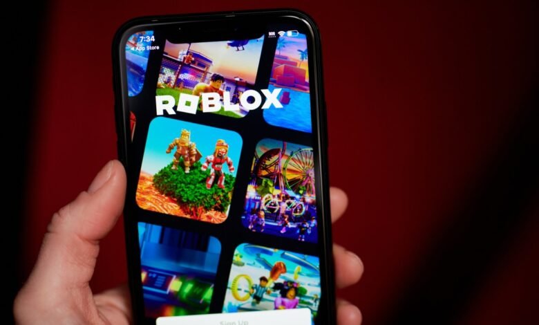 Close-up of a hand holding a smartphone displaying the Roblox app interface.