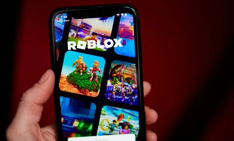 Close-up of a hand holding a smartphone displaying the Roblox app interface.