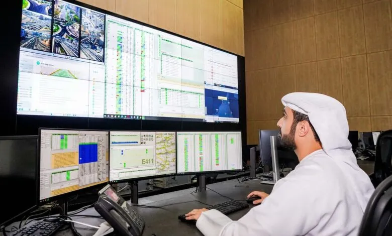 Man in traditional Emirati clothing monitors a large screen displaying traffic data and surveillance feeds.