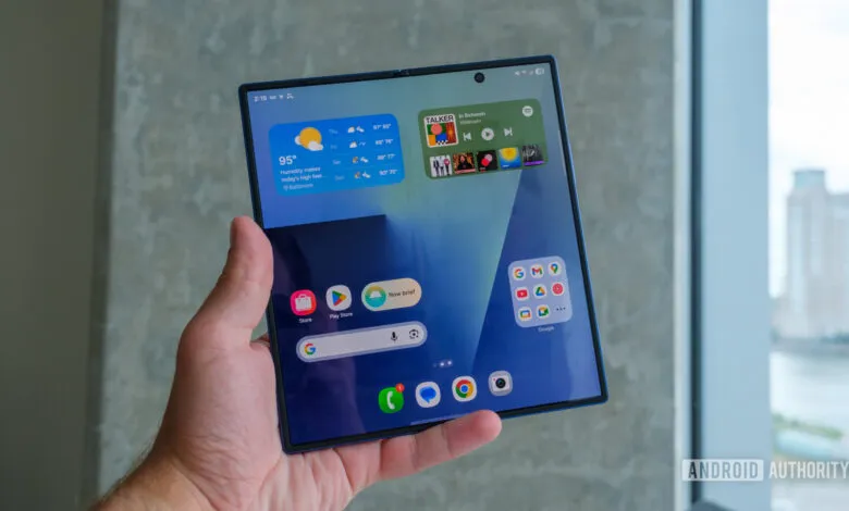 Hand holding open Samsung Galaxy Z Fold 7, showcasing its large screen and various apps.