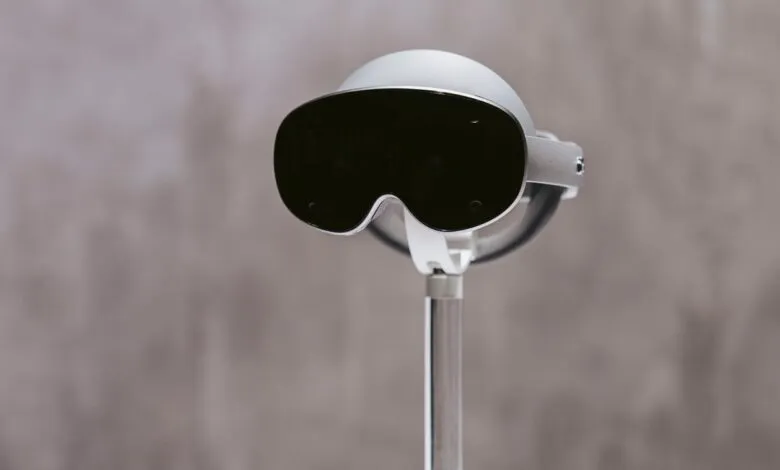 Close-up of a sleek, silver Samsung Project Moohan VR headset displayed on a stand against a muted gray background.