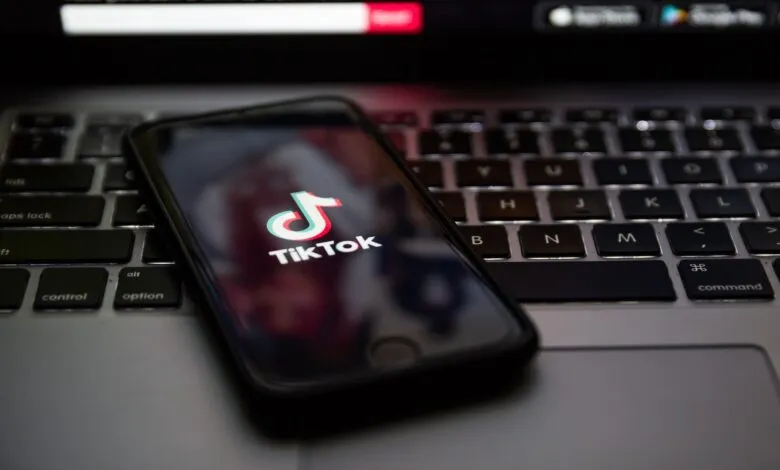 Smartphone displaying the TikTok logo on a laptop keyboard.