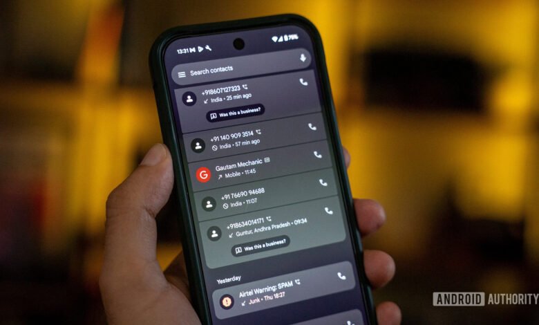 Close-up of a hand holding a smartphone displaying a list of recent calls, including spam warnings.