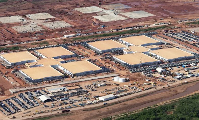 Aerial view of a large-scale construction site, featuring numerous buildings under construction and extensive surrounding land.