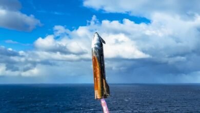 SpaceX Starship prototype ascending over a blue ocean under a partly cloudy sky.