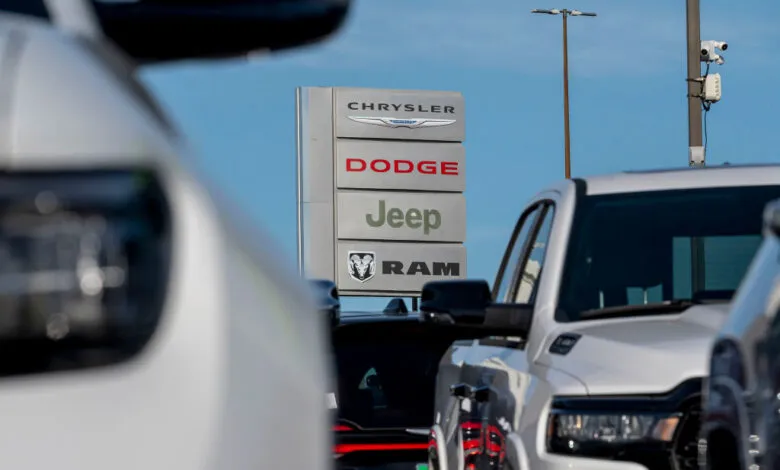 Chrysler, Dodge, Jeep, and Ram dealership sign with cars in the foreground.