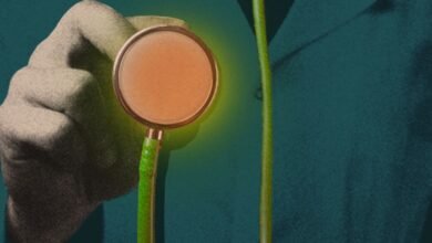 Close-up of a hand holding a stethoscope with a glowing, orange-toned diaphragm against a teal background.