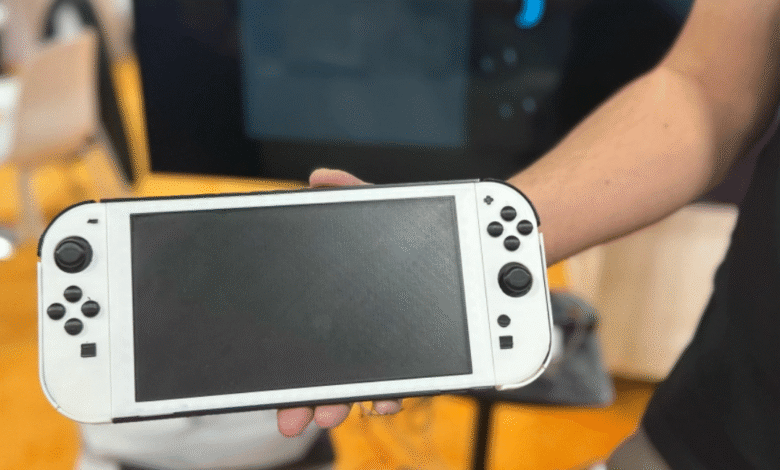 Person holding a white Nintendo Switch console with a black screen.