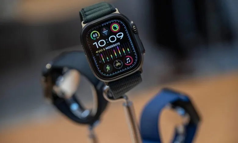 Close-up of Apple Watch Ultra 3 with dark gray titanium case and olive green strap, displaying time and fitness data.