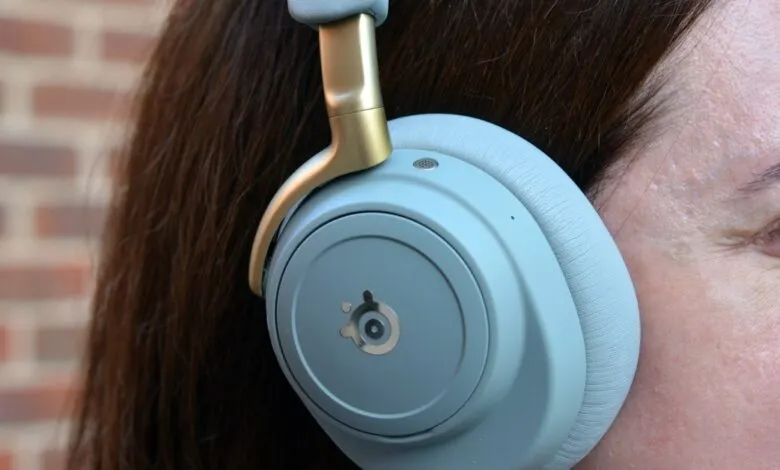 Close-up of a person wearing light blue over-ear headphones with gold accents.