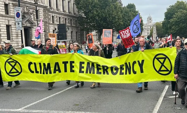 Climate activists march in London, carrying a large banner that reads 'Climate Emergency'.