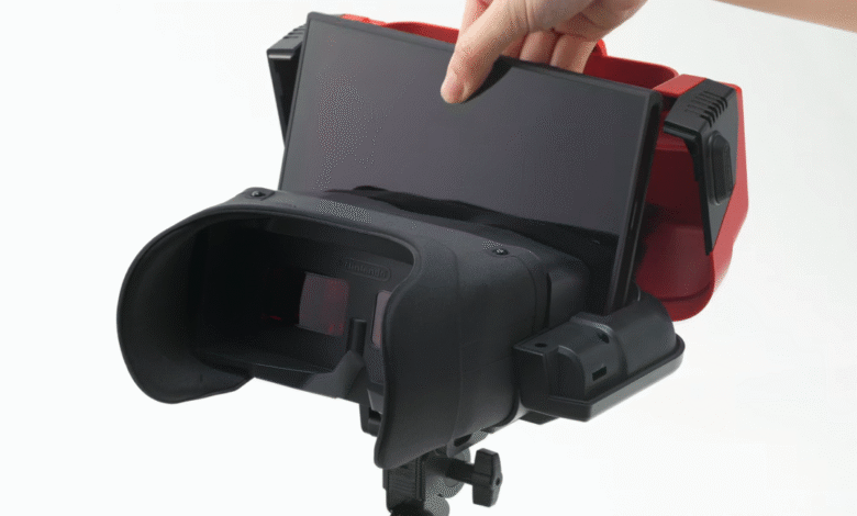 Close-up of a person inserting a screen into a Nintendo Virtual Boy accessory. The device is black and red, mounted on a tripod.